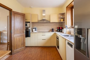 A compact kitchen with wooden cabinets, a microwave, a stove, a coffee maker, and a refrigerator.