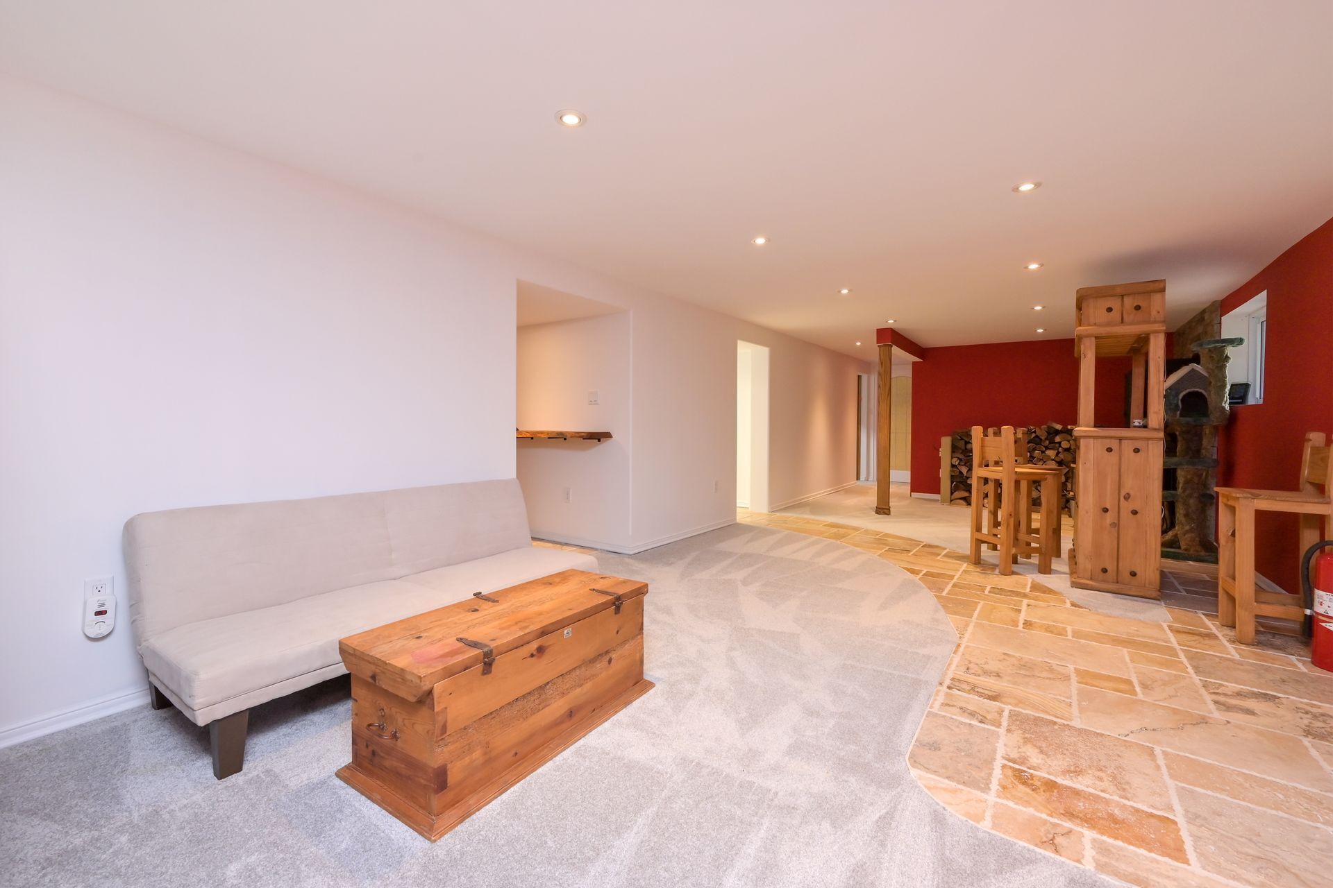 En rummelig opholdsstue med en beige sofa, en træskuffe og en stengulv.