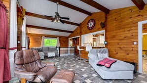 A cozy cabin interior with a rocking chair, a sofa, and a checkered floor.