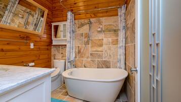 A bathroom with a freestanding bathtub, a toilet, and a sink.
