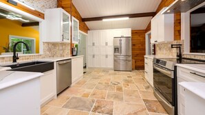 A modern kitchen with white cabinetry, a stainless steel refrigerator, and a built-in oven.