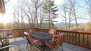 Eine Terrasse mit Tisch und Stühlen mit Blick auf eine bewaldete Landschaft.