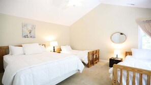 Ein Schlafzimmer mit zwei Betten, einem Nachttisch mit Lampe, einem runden Spiegel und einem Bild an der Wand.