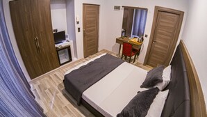 Une chambre d’hôtel avec un lit, un bureau, un miroir et une armoire.