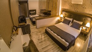 Une chambre d’hôtel comprenant un lit, deux tables de chevet, un bureau, une chaise, un téléviseur et une cloison.