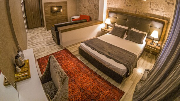 Une chambre d’hôtel moderne dotée d’un grand lit, d’un coin salon, d’une petite table et d’une armoire intégrée.