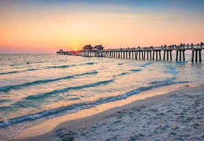 A pier extending into the sea with a sunset in the background.