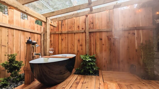 A wooden deck with a hot tub, a sink, and a glass of wine.