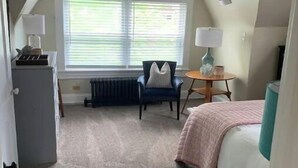Quarto com cama, poltrona, escrivaninha e radiador.