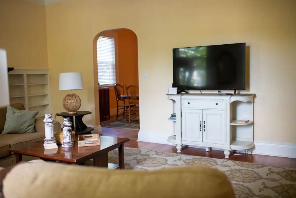 A living room with a television on a white cabinet, a sofa, a coffee table, and a lamp.