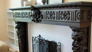 Un camino con elaborate decorazioni intagliate e una mensola con cornici e fotografie.