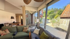 A modern living room with a green sofa, a grey sofa, and a dining area with wooden furniture. - Charming Stone Retreat on 19ha Private Estate | Valley Views & Total Privacy (Salvador do Monte)