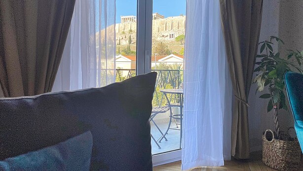 Una habitación con vistas a un edificio histórico, un balcón con una silla y una planta en maceta.