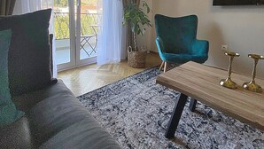 Una sala de estar con un sofá, un sillón verde azulado, una mesita de centro y una planta en maceta.
