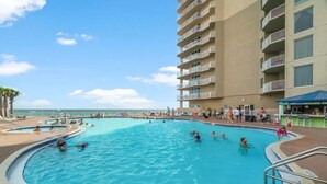 Una amplia piscina al aire libre rodeada por un edificio de varios pisos con balcones.