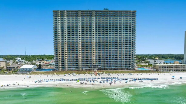 Un hotel de gran altura con vista a la playa, varios balcones y una zona de piscina.