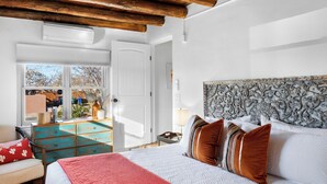 Una camera da letto con un letto grande, travi in legno a soffitto, un comò e vista sull'esterno.