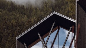 A wooden cabin with a sloped roof and large windows.