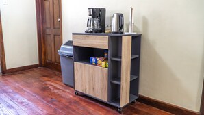 A small wooden cabinet with a coffee maker, a kettle, and a trash can. - Chillinn at Duke (Kingston)