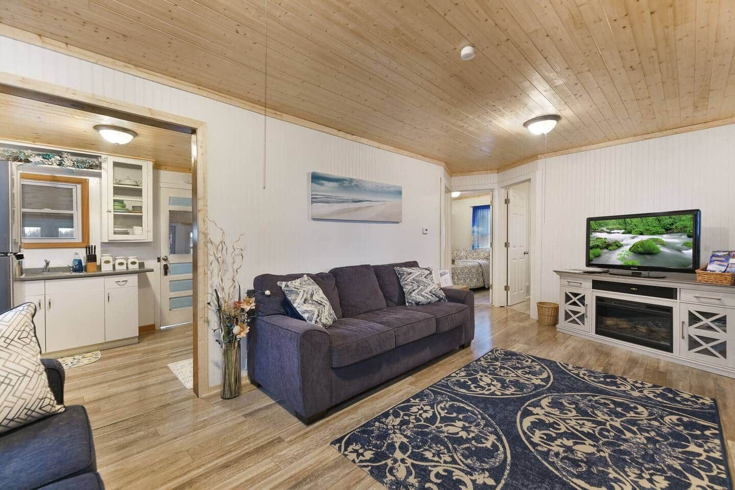 Una sala de estar con un sofá, una televisión y un tapete decorativo.