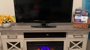 Een televisie op een houten tv-meubel met een haard eronder.