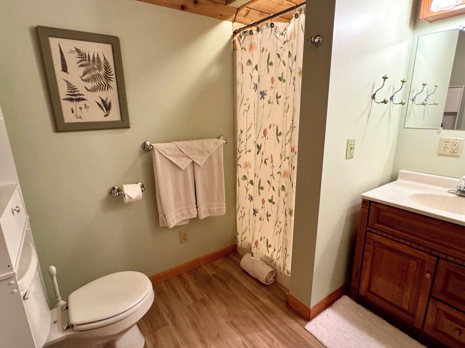 Un baño con inodoro, cortina de ducha, lavabo y espejo.