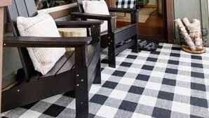 Une pièce chaleureuse avec deux chaises à ossature en bois, un sol à carreaux et une grande fenêtre.