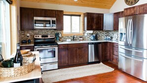 Une cuisine moderne avec des meubles en bois foncé, des appareils électroménagers en acier inoxydable et une grande horloge murale.