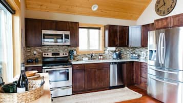 Una cocina moderna con armarios de madera, electrodomésticos de acero inoxidable y un reloj de pared grande.