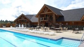 Un espace piscine avec des chaises longues et un bâtiment doté d’un balcon.