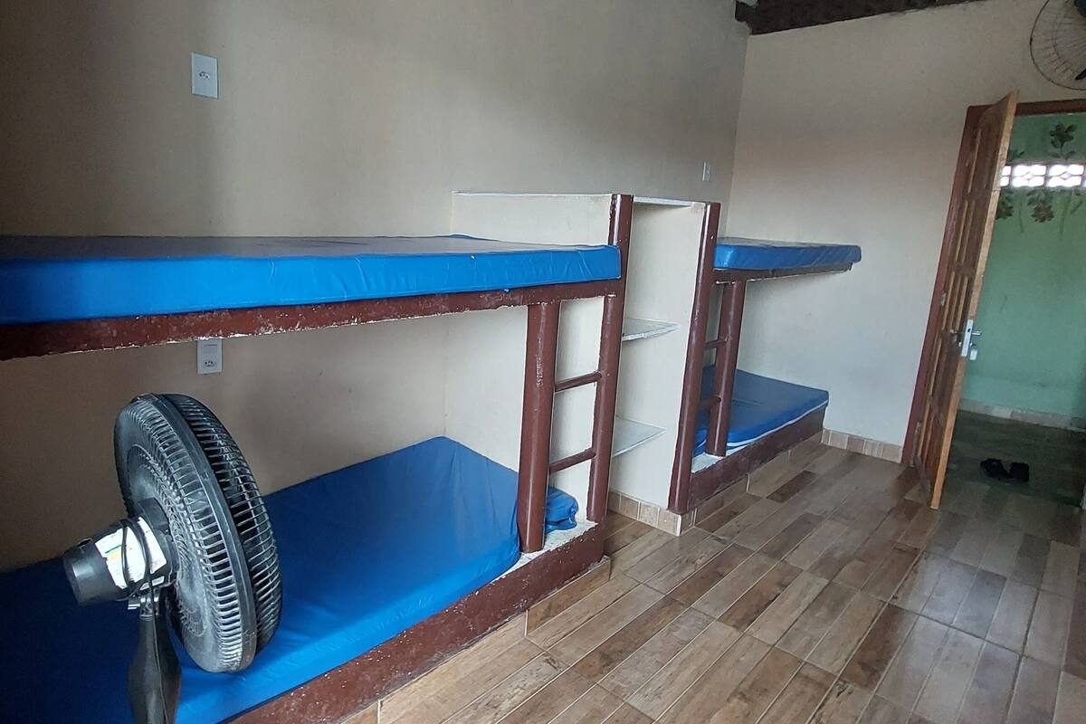 A room with bunk beds, a fan, and a green door.