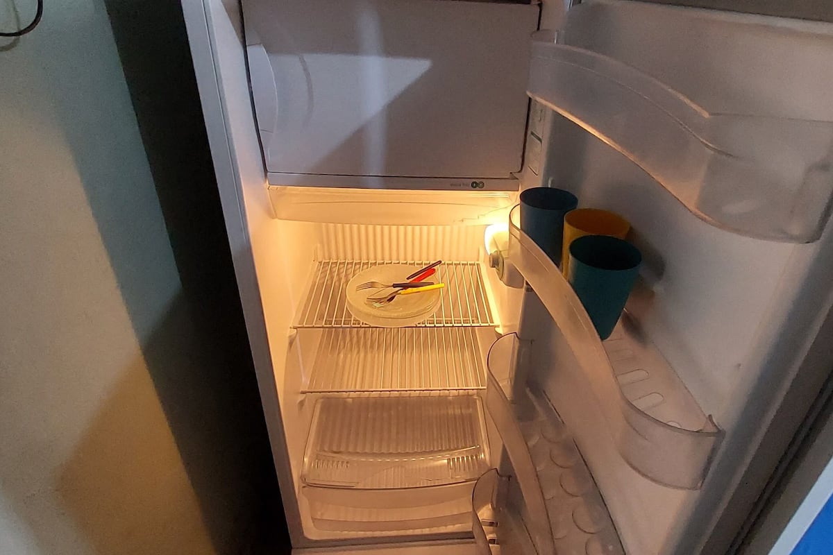 A refrigerator with a freezer compartment containing a plate with utensils and a carton of milk.