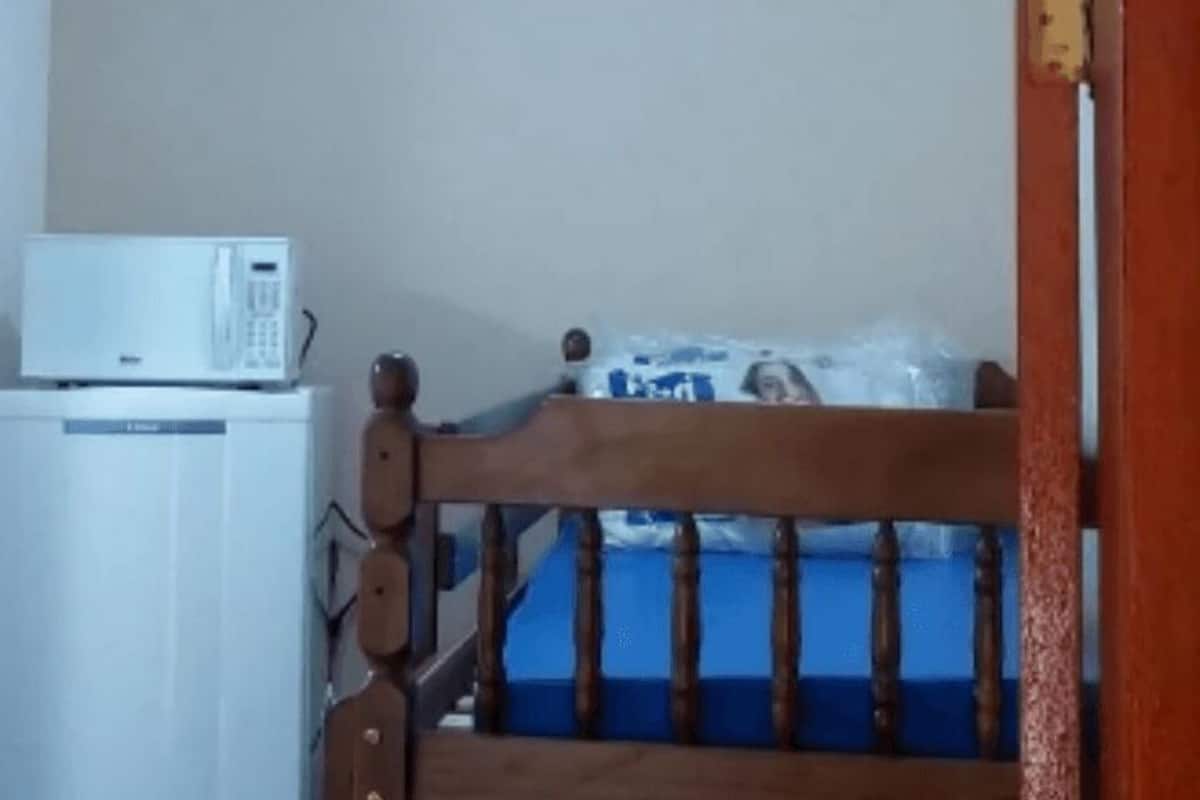 A room with a white refrigerator, a wooden chair, and a blue bed.