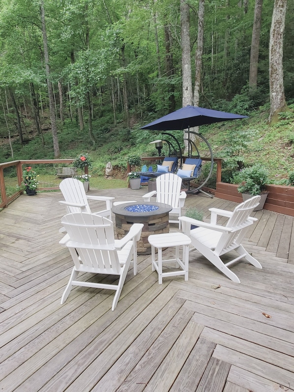 Relax in a serene outdoor space surrounded by lush greenery and a central fire pit.