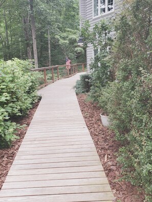 Guests enter through a serene pathway surrounded by lush greenery and trees.