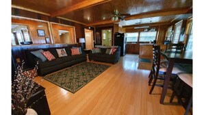 A spacious living area with a large sofa set, a dining table, and a kitchen in the background.