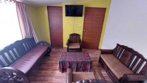 Un salon comprenant un canapé, une petite table et un téléviseur fixé au mur.
