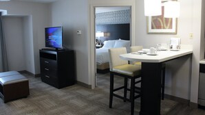 Une chambre d’hôtel comprenant un lit, un bureau avec un ordinateur, une chaise, une petite table et un téléviseur.