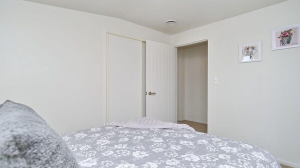 Quarto com uma cama, uma porta e um corredor.