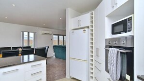 A modern kitchen with white cabinets, a built-in oven, and a microwave.