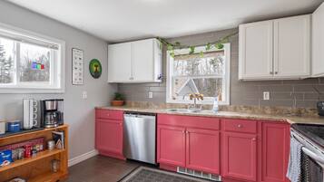 A kitchen with white upper cabinets, a stainless steel dishwasher, and a granite countertop.