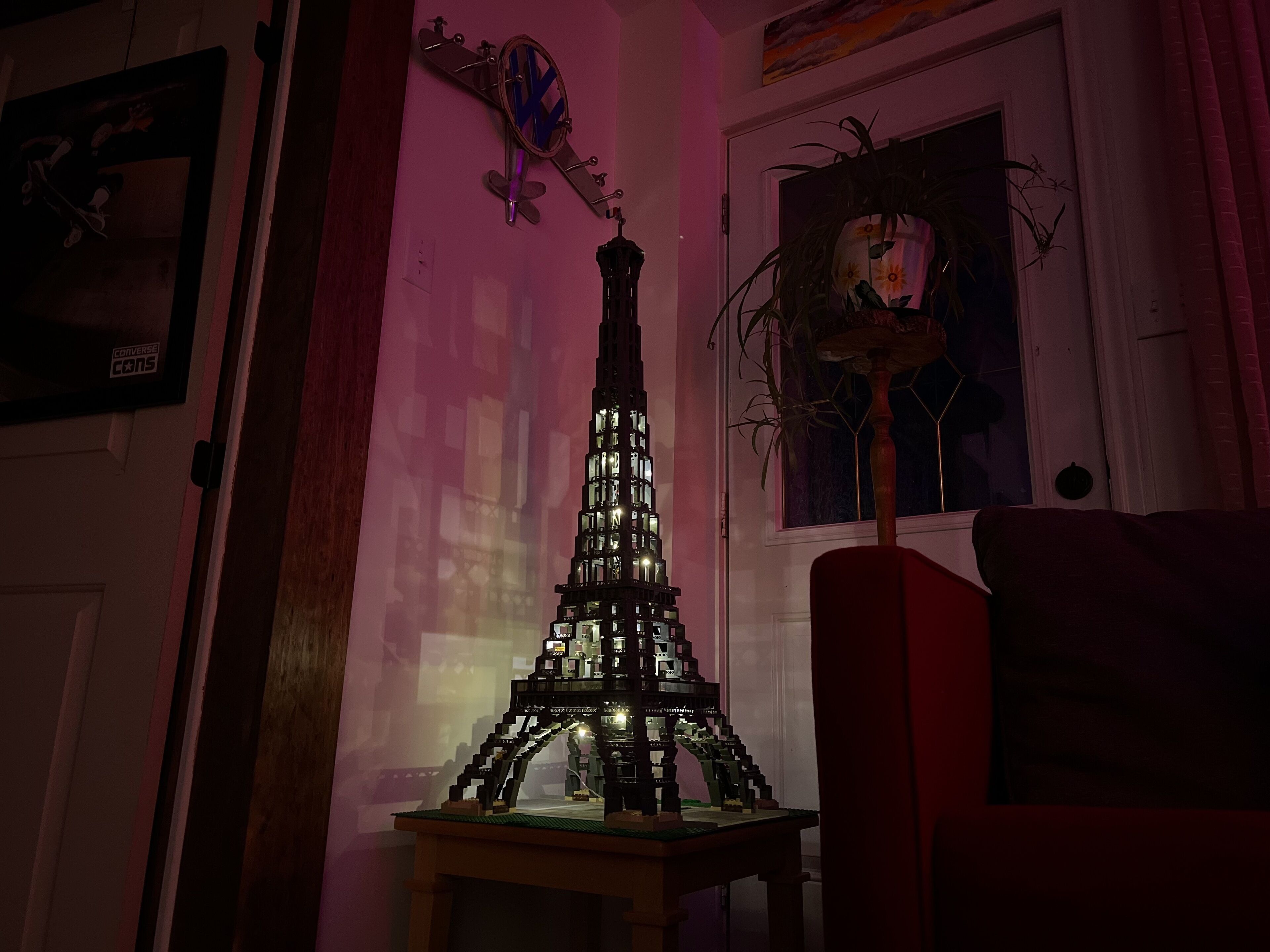 A model of the Eiffel Tower in a room with a door, a window with a plant, and a painting on the wall.