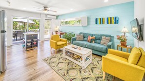 A living room with a teal wall, yellow armchairs, a green sofa, and a coffee table with books. - Charming 3 Bedroom Suite 200 steps to Beach, car available (Freeport)