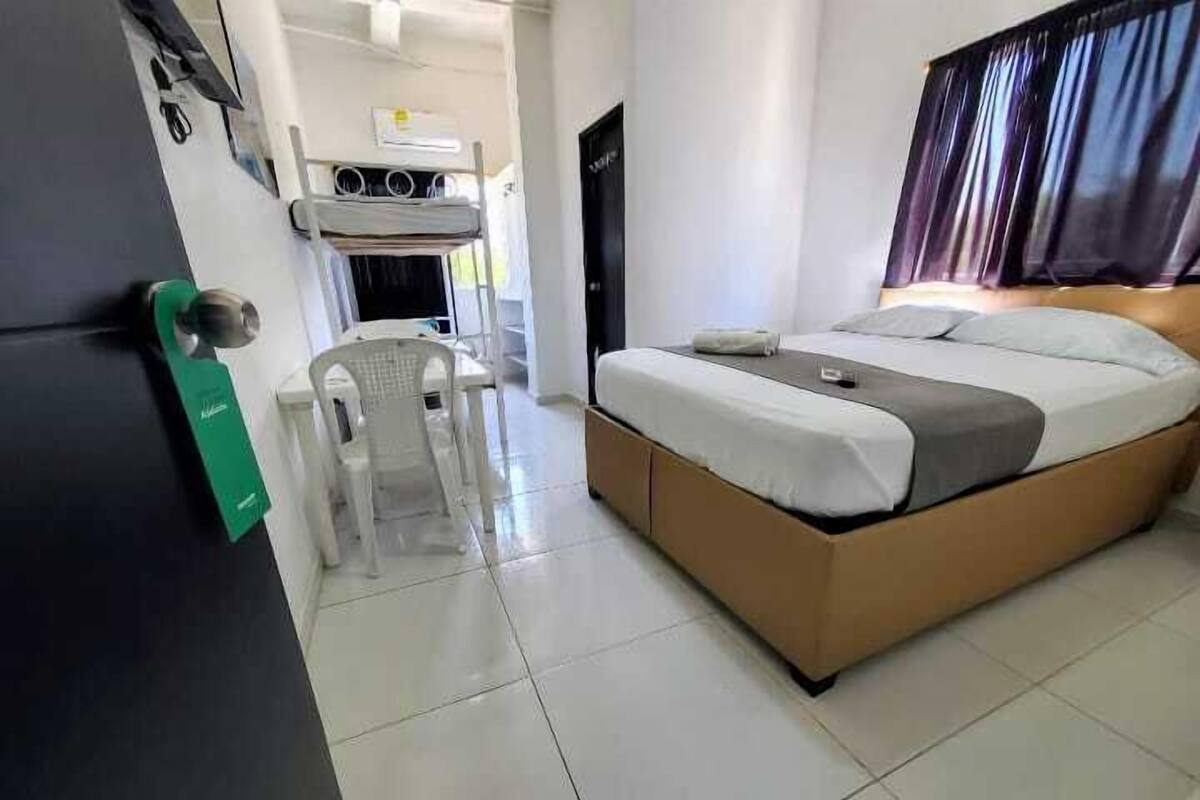 A hotel room with a bed, a chair, a desk, and a kitchenette.