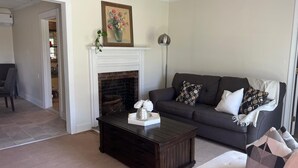 A living room with a fireplace, a sofa, a coffee table, and a painting on the wall.