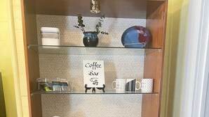 A kitchenette with a Keurig coffee maker, a coffee bar sign, and a small cabinet with a red folder.