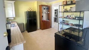 A compact kitchen with a refrigerator, wooden cabinets, and a metal shelving unit.