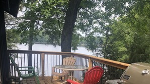 A wooden deck with a grill, chairs, and a lantern. - Lake Front Cottage Property  (Bracebridge)