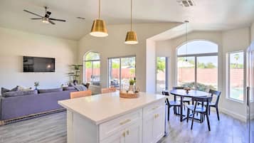 A modern kitchen with a central island, pendant lighting, and a ceiling fan.