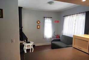 Ein Wohnzimmer mit einer Couch, einem kleinen weißen Tisch, einer Mikrowelle und einem Kamin.